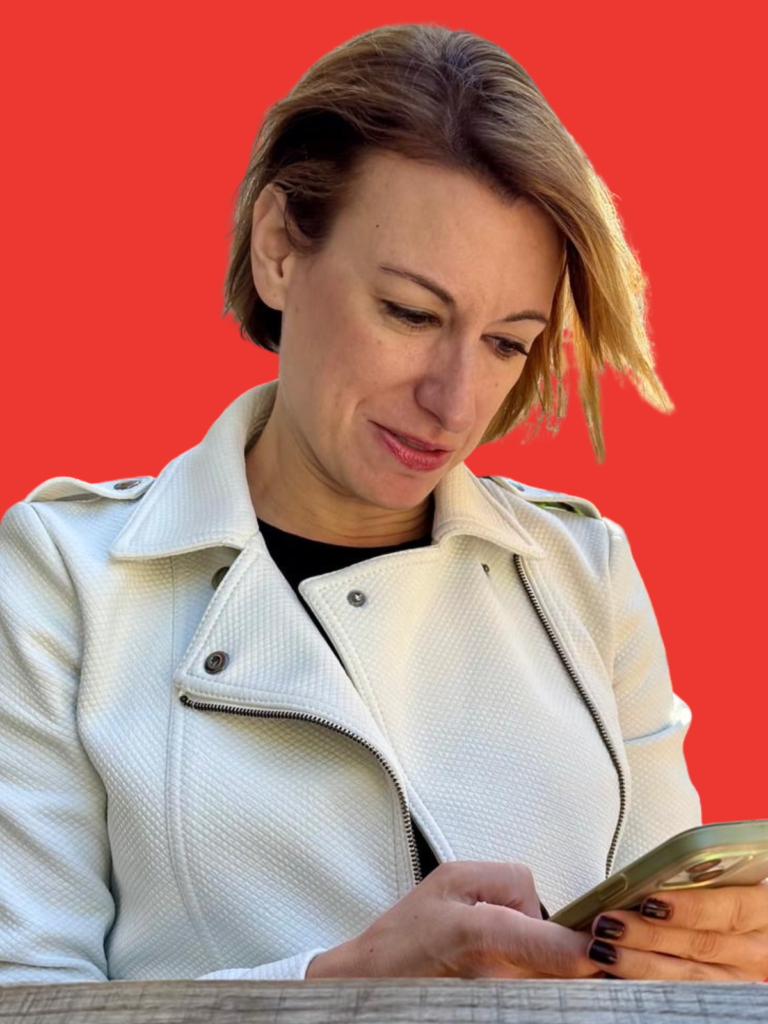 Robyn is wearing a white jacket and typing on her phone. The background is red.